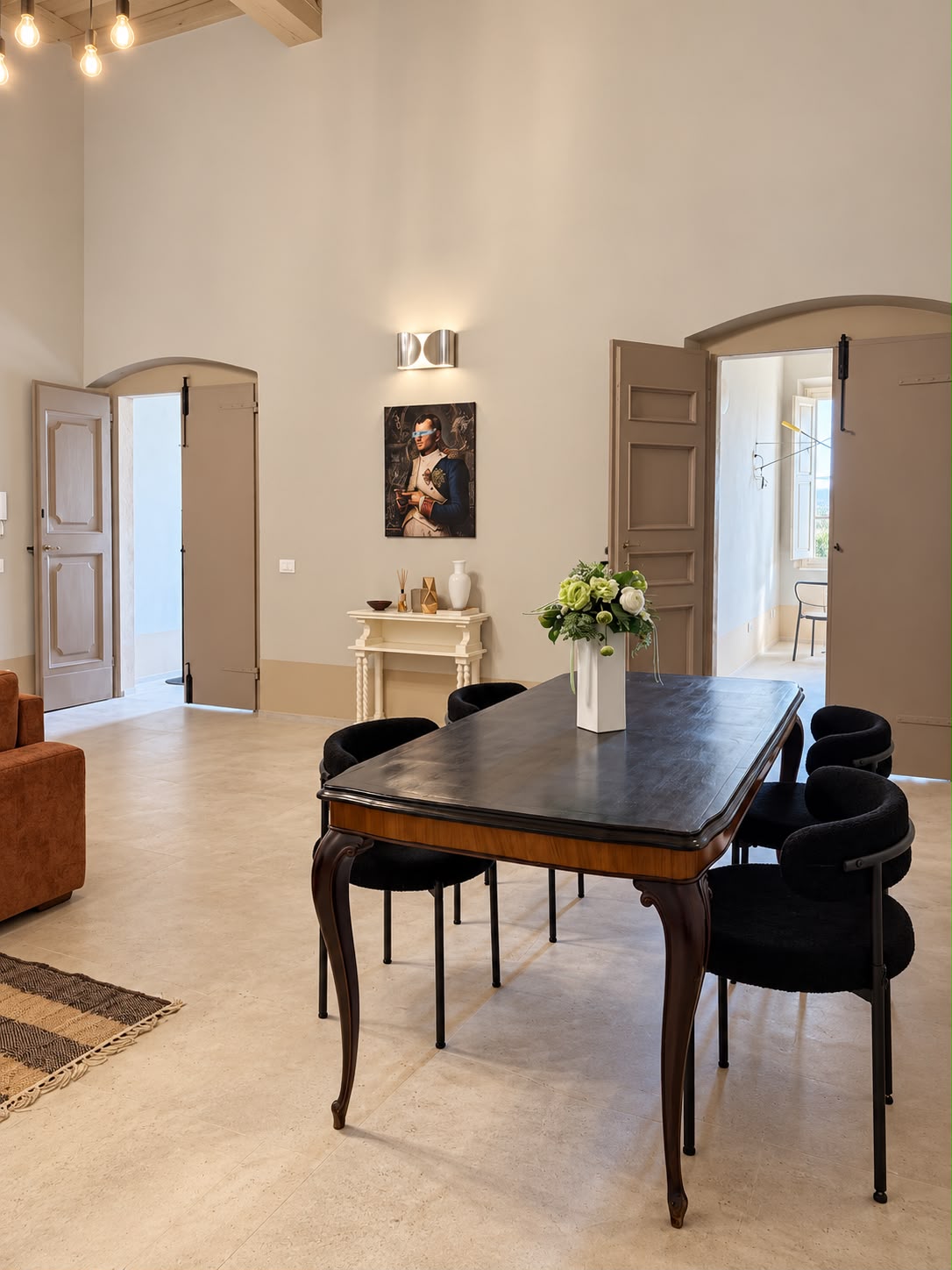 Zona soggiorno del living, enorme e luminosa, con divano letto, soffitto a travi a vista e tavolo da pranzo sullo sfondo.