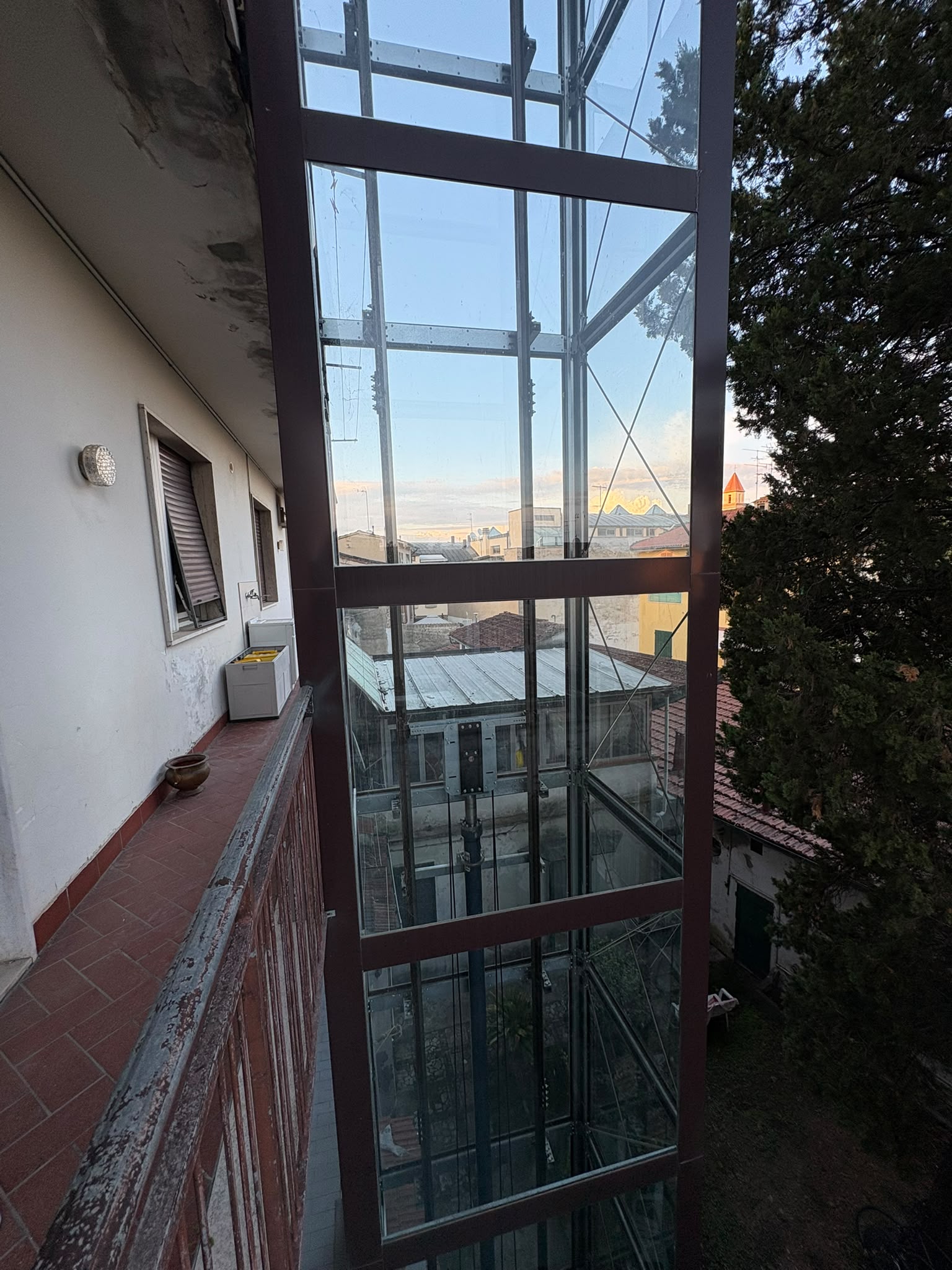 Ascensore privato in vetro e acciaio che sale lungo il terrazzo dell'appartamento.