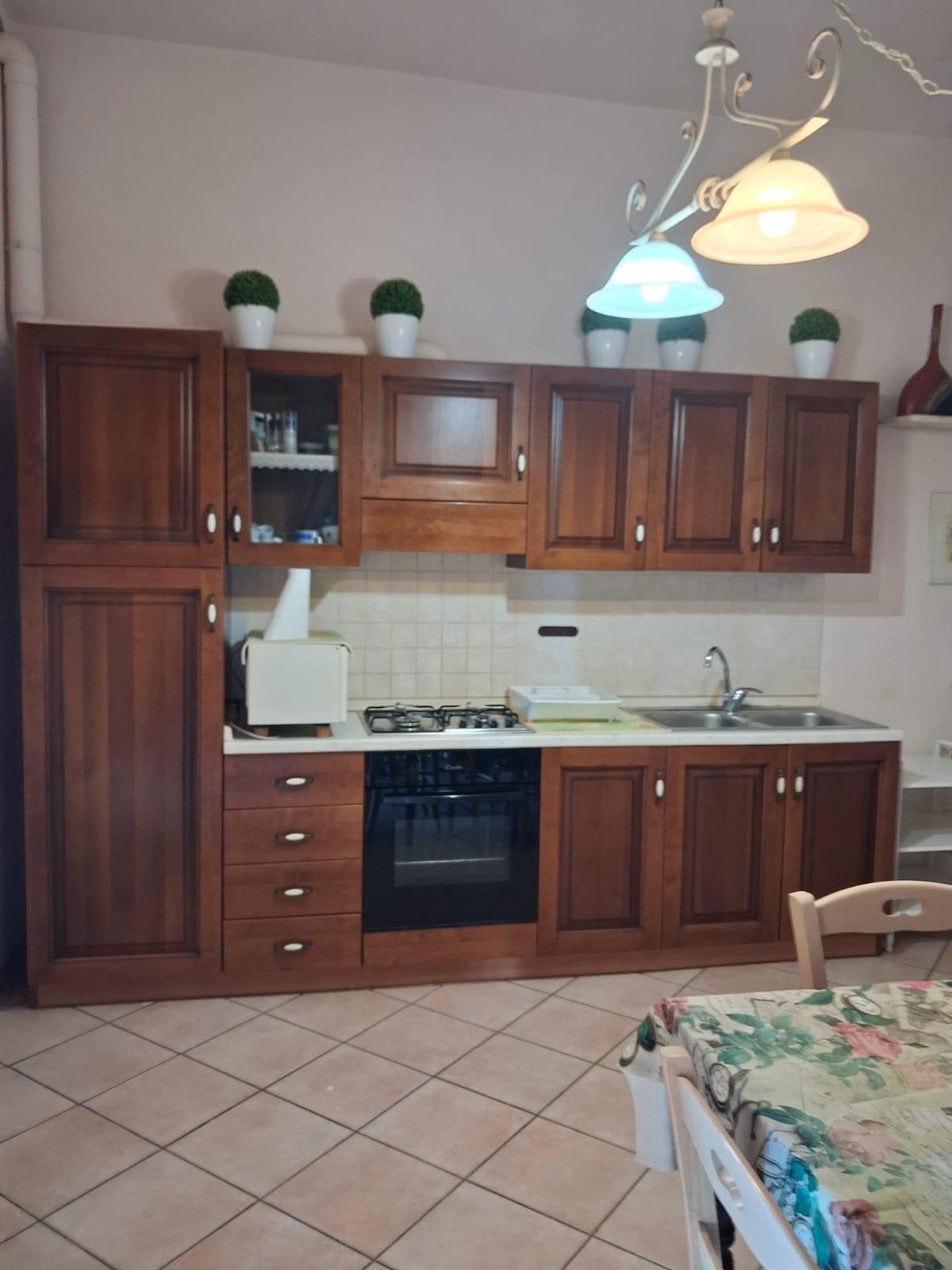 Cucina in legno completamente arredata dell'appartamento in affitto a Montopoli in Val d'Arno, con zona tv.